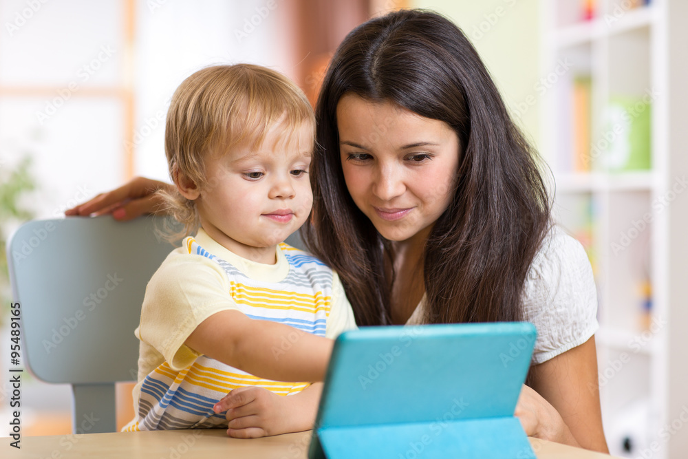 Mother and son child playing with tablet computer indoors Mother and son child playing with tablet computer indoors
