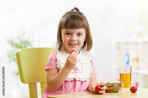 Child girl eating vegetable...