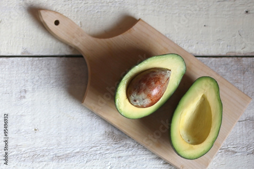 Avocado cut in half on wooden board and rustic white table. Top view. 