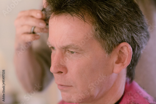 Senior man having haircut and close up of hairdresser's hands