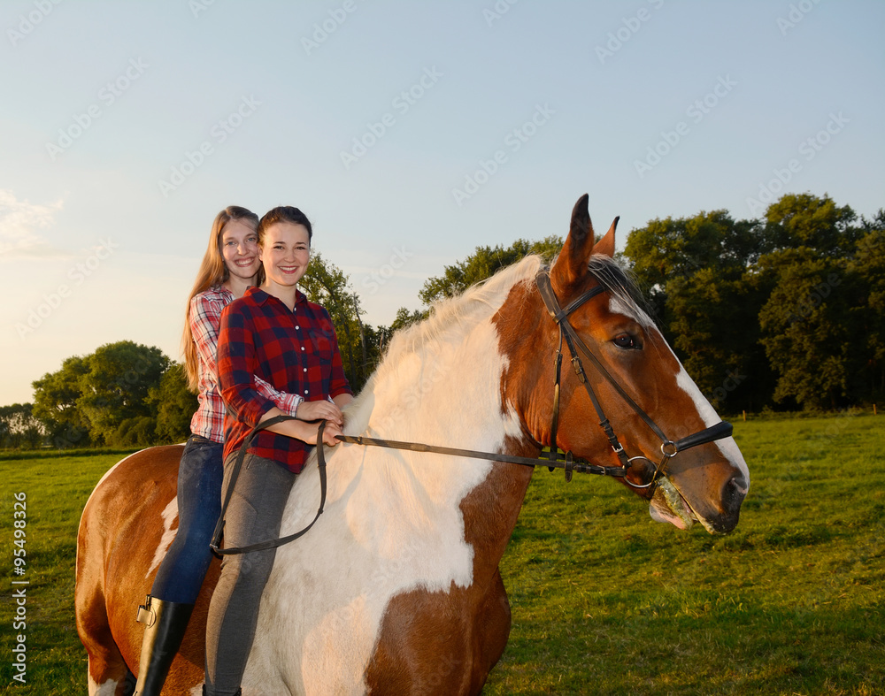 Zwei junge Frauen reiten auf einem Pferd Stock Photo | Adobe Stock