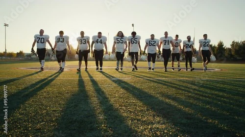 A football team walking toward the camera in slow motion, with lens flare

