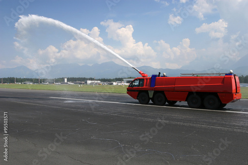 Big red Airport Firetruck using a water cannon on the runway