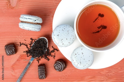 Photos Light blue french macarons with earl gray tea and chocolate on red wooden table