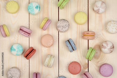 A lot of multicolored macarons on wooden background