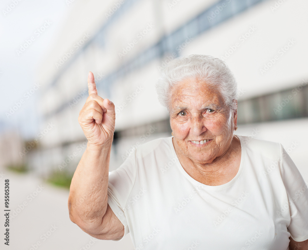 portrait of adorable old woman pointing up with her finger portrait of adorable old woman pointing up with her finger