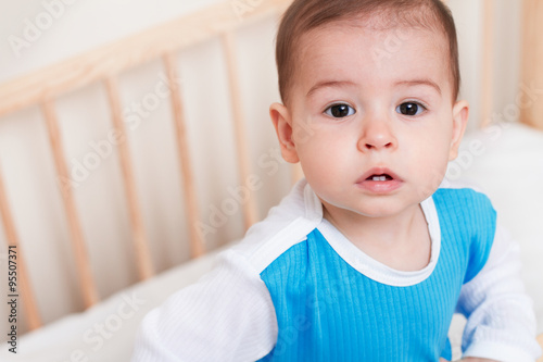 Beautiful cute baby toddler look at one side on the white bed