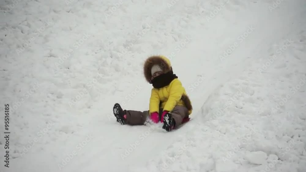 Cute little girl riding down a steep hill on a sledge Cute little girl riding down a steep hill on a sledge