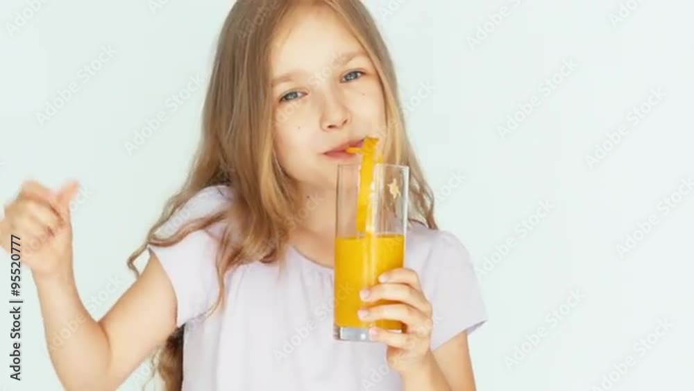 Girl drinking orange juice and dancing and smiling at camera. Girl with beautiful blonde hair on a white background. Thumb up. Ok. Closeup Girl drinking orange juice and dancing and smiling at camera. Girl with beautiful blonde hair on a white background. Thumb up. Ok. Closeup