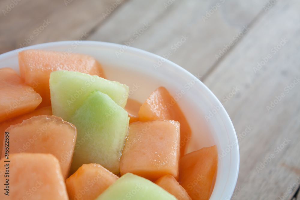closeup melon slice in white dish with wood table background closeup melon slice in white dish with wood table background