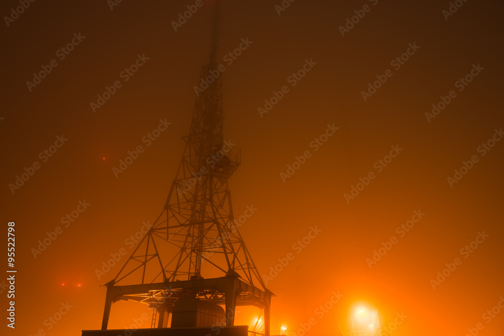 Communication tower in fog over hill Communication tower in fog over hill