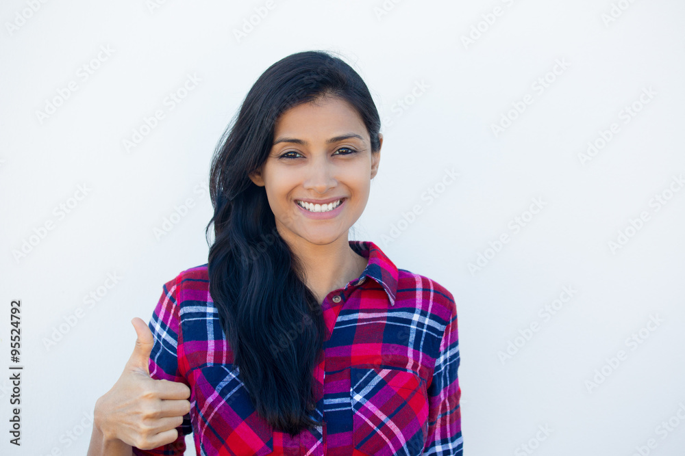Closeup portrait of young pretty woman with one thumbs up sign gesture, plaid red shirt, isolated white wall background. Positive emotion facial expression feelings, signs and symbols, body language Closeup portrait of young pretty woman with one thumbs up sign gesture, plaid red shirt, isolated white wall background. Positive emotion facial expression feelings, signs and symbols, body language