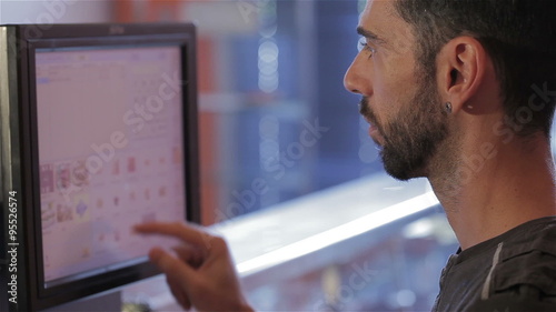 Man at cash register typing on the touchscreen