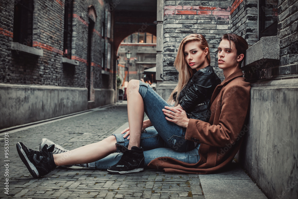 Young trendy man and woman posing in brick walls street Young trendy man and woman posing in brick walls street