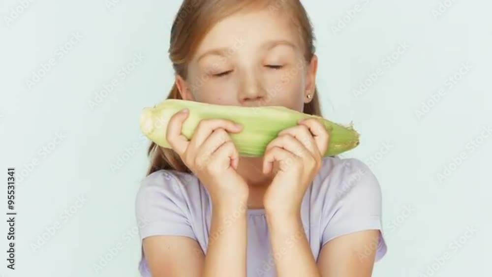Girl showing corn and sniffing it and laughing. Closeup Girl showing corn and sniffing it and laughing. Closeup