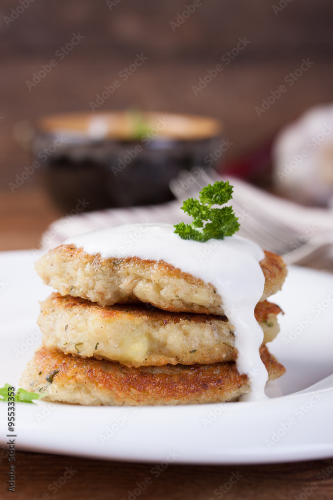 Fried potato pancakes with oatmeal and basil on a white ceramic plate.
