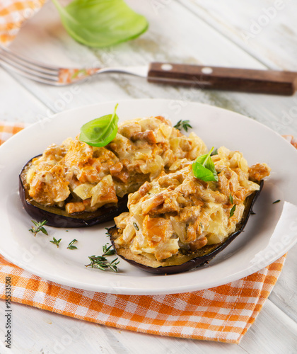 Baked eggplant with chanterelles on a white plate.