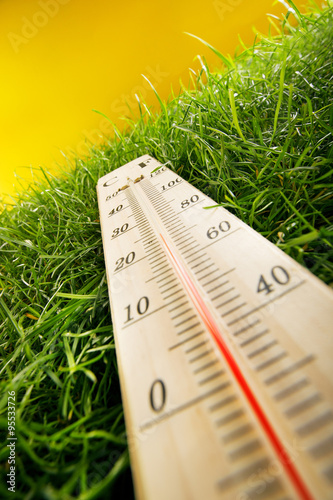 thermometer and fresh grass on yellow background