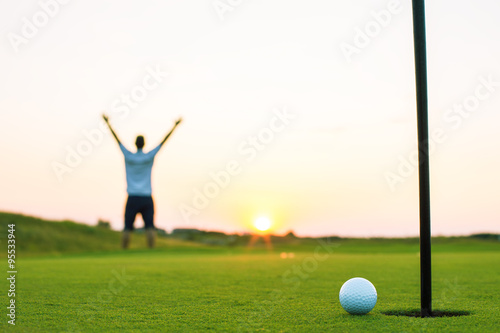 Happy golf player on a golf court at sunset