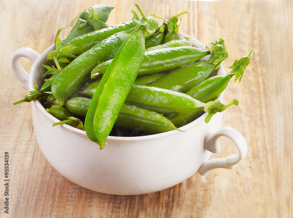 Green peas in white bowl on a wooden background. Green peas in white bowl on a wooden background.