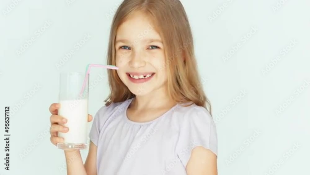 Happy child drinking milk. Girl with beautiful blond hair on a white background. Thumb up. Ok. Closeup Happy child drinking milk. Girl with beautiful blond hair on a white background. Thumb up. Ok. Closeup