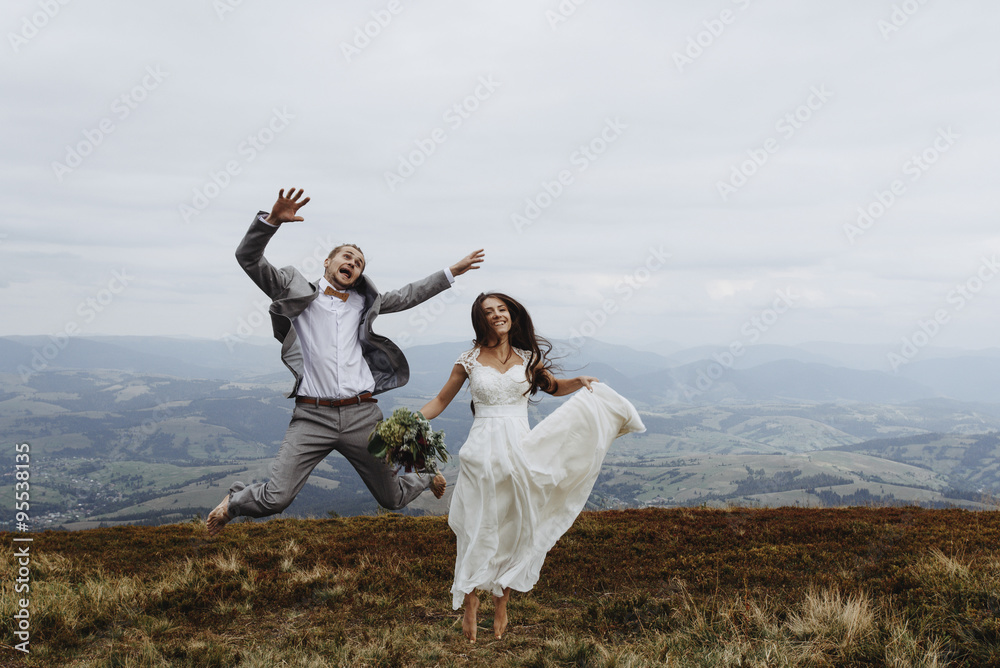 beautiful fabulous happy  bride and stylish groom jumping  on th