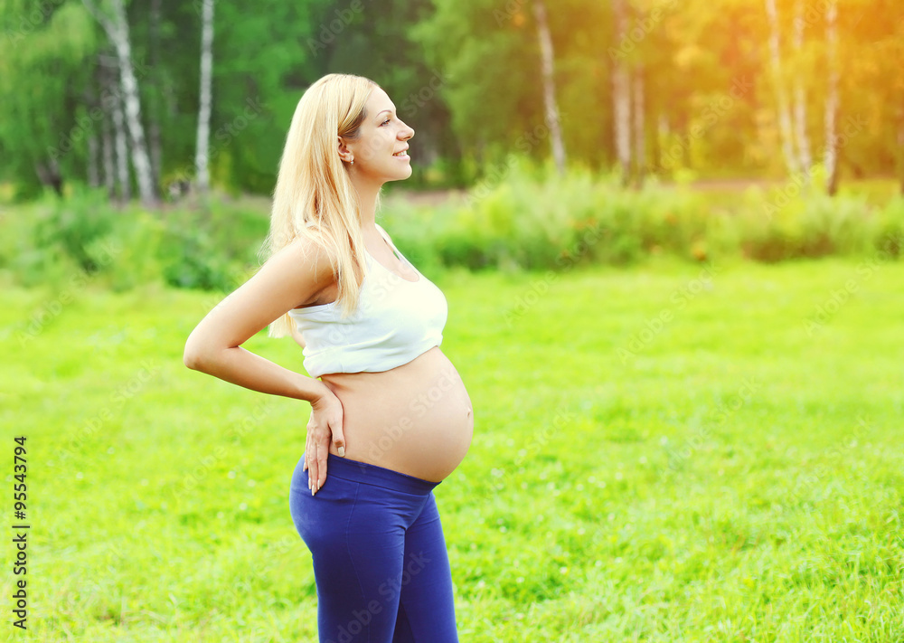 Beautiful young pregnant woman outdoors over summer background Beautiful young pregnant woman outdoors over summer background