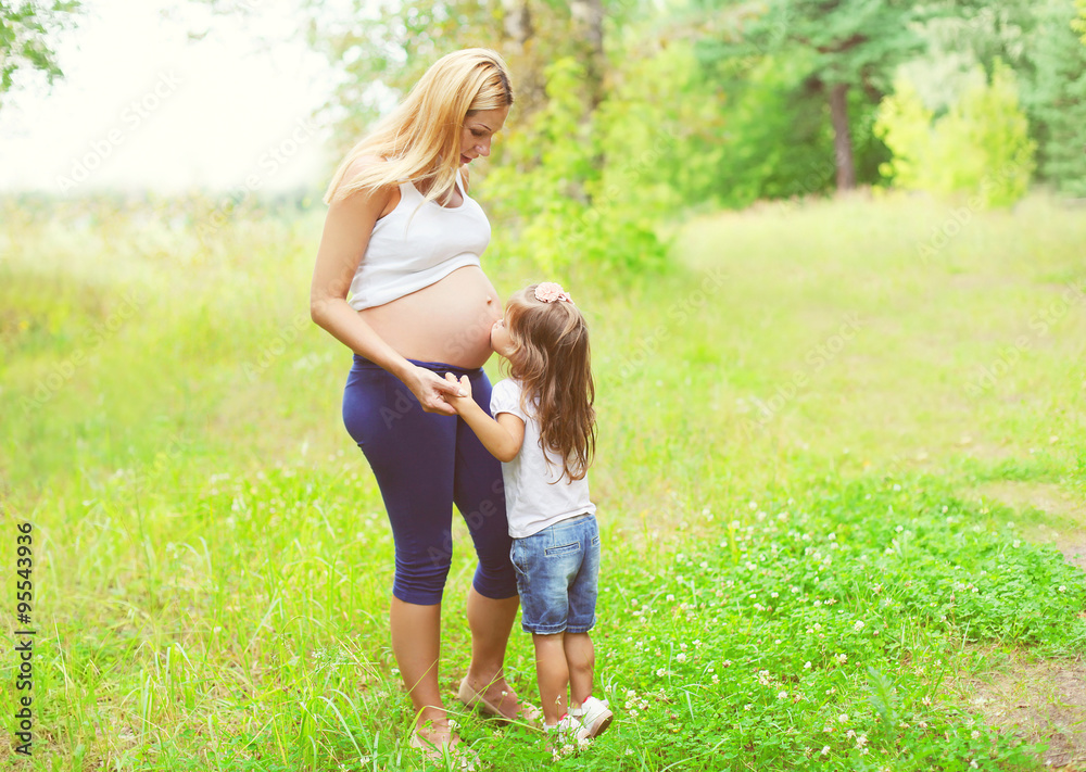 Happy pregnant woman, little child daughter kissing tummy mother Happy pregnant woman, little child daughter kissing tummy mother