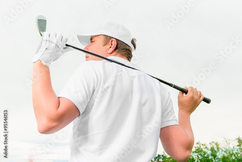 man holding a golf club behind his back
