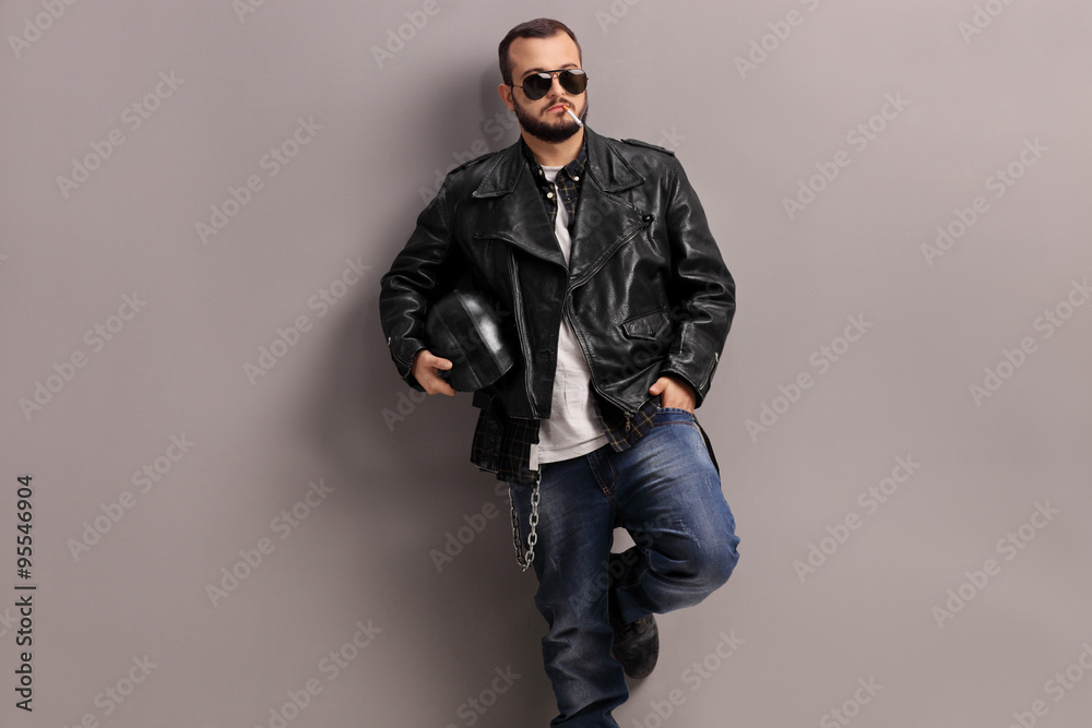 Young male biker leaning against a wall Young male biker leaning against a wall
