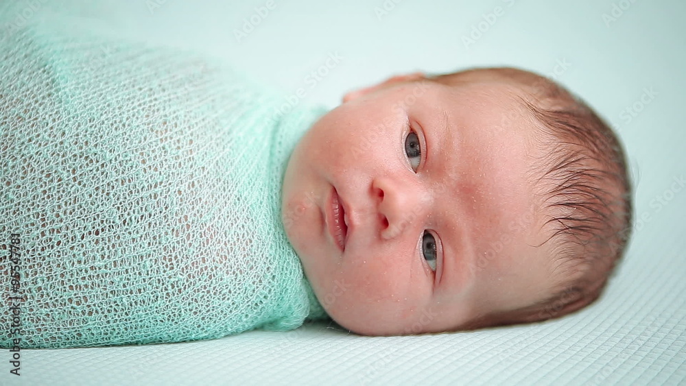 Blue-eyed newborn baby lying and looking around in wonder Blue-eyed newborn baby lying and looking around in wonder