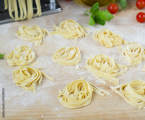 fresh homemade pasta machine pasta, basil, tomatoes on a wooden