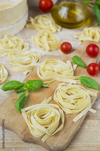 fresh homemade pasta machine pasta, basil,. tomatoes on a wooden