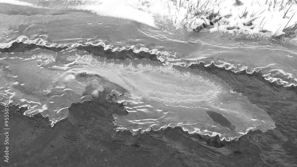 brook partly covered with ice in winter in black and white