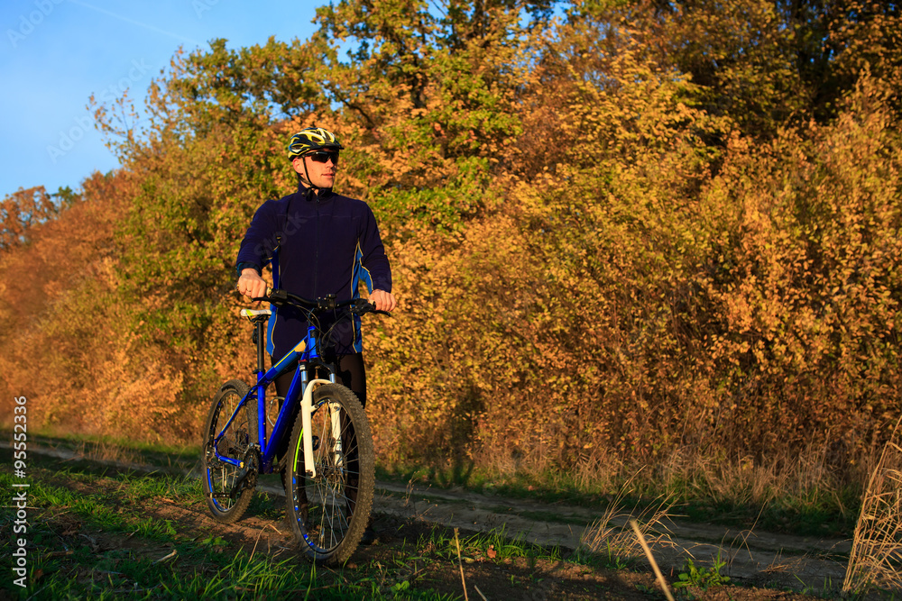 Obraz premium young adult cyclist riding mountain bike in the countryside