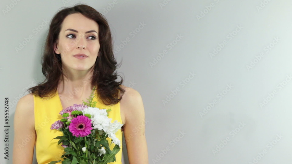 Young woman holding a bouquet of flowers smiling and waiting for someone Young woman holding a bouquet of flowers smiling and waiting for someone
