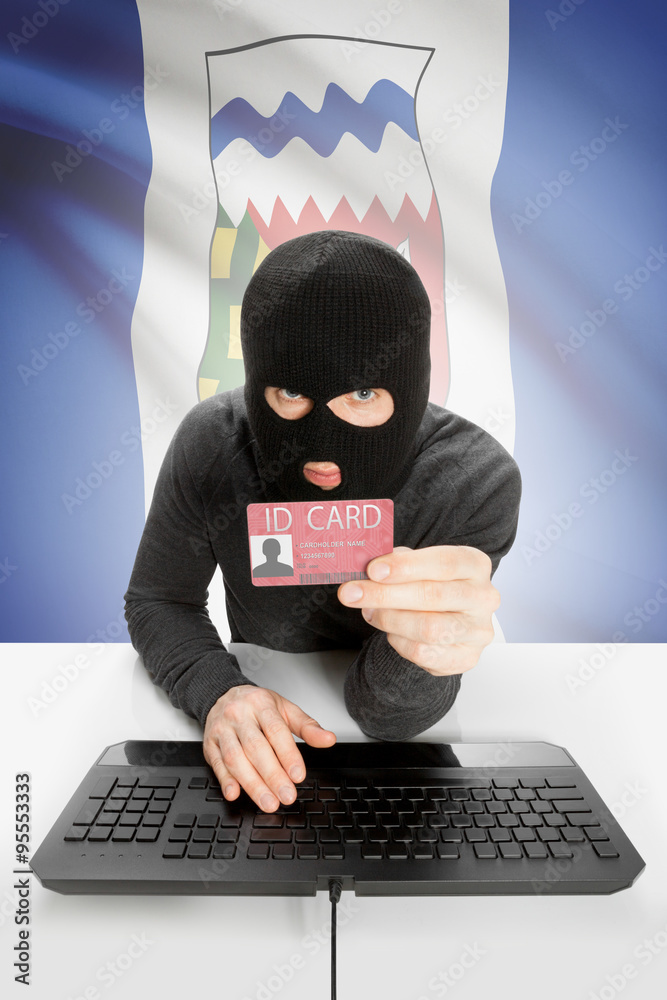 Hacker with Canadian province flag on background holding ID card in hand - Northwest Territories Hacker with Canadian province flag on background holding ID card in hand - Northwest Territories
