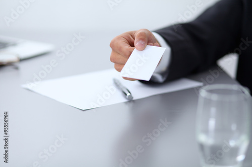 Close-up of businessman giving a business card, sitting at the table