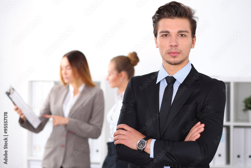Cheerful business man in office with colleagues in the background, sturt  up team