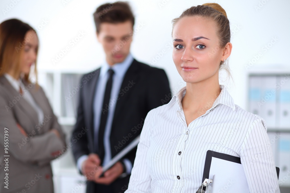 Pretty businesswoman in office with colleagues in the background Pretty businesswoman in office with colleagues in the background