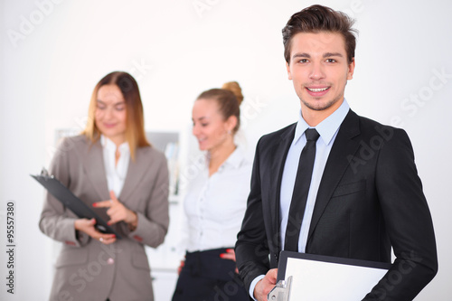 Cheerful business man in office with colleagues in the background, sturt up team
