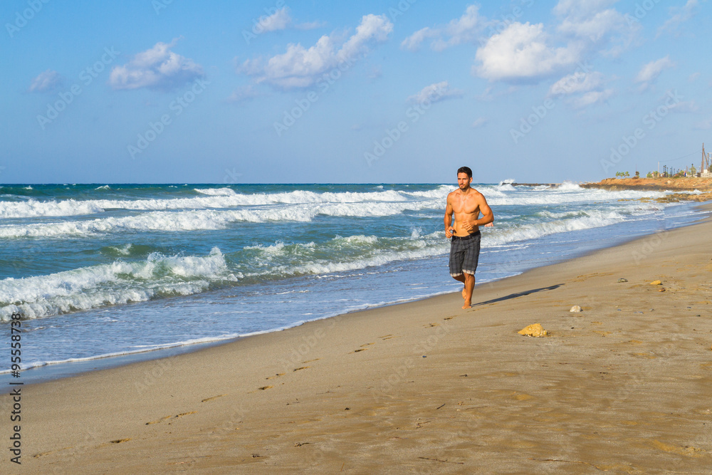 Young man in his twenties jogging on a sandy beach
