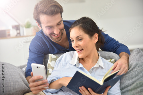 Couple at home entertaining and reading message on smartphone