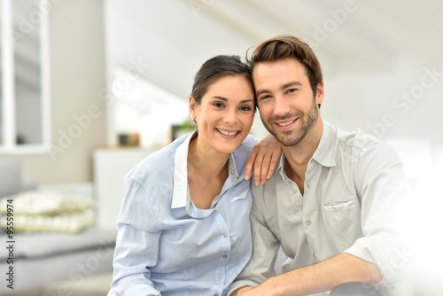 Portrait of cheerful couple sitting in sofa at home © goodluz