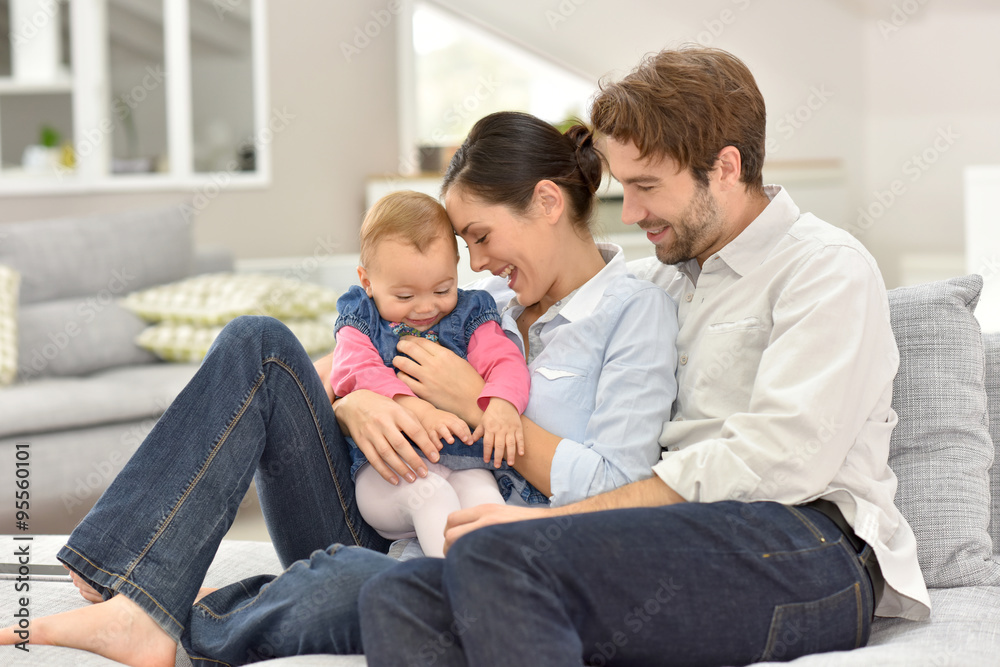 Young parents with baby sitting in sofa at home