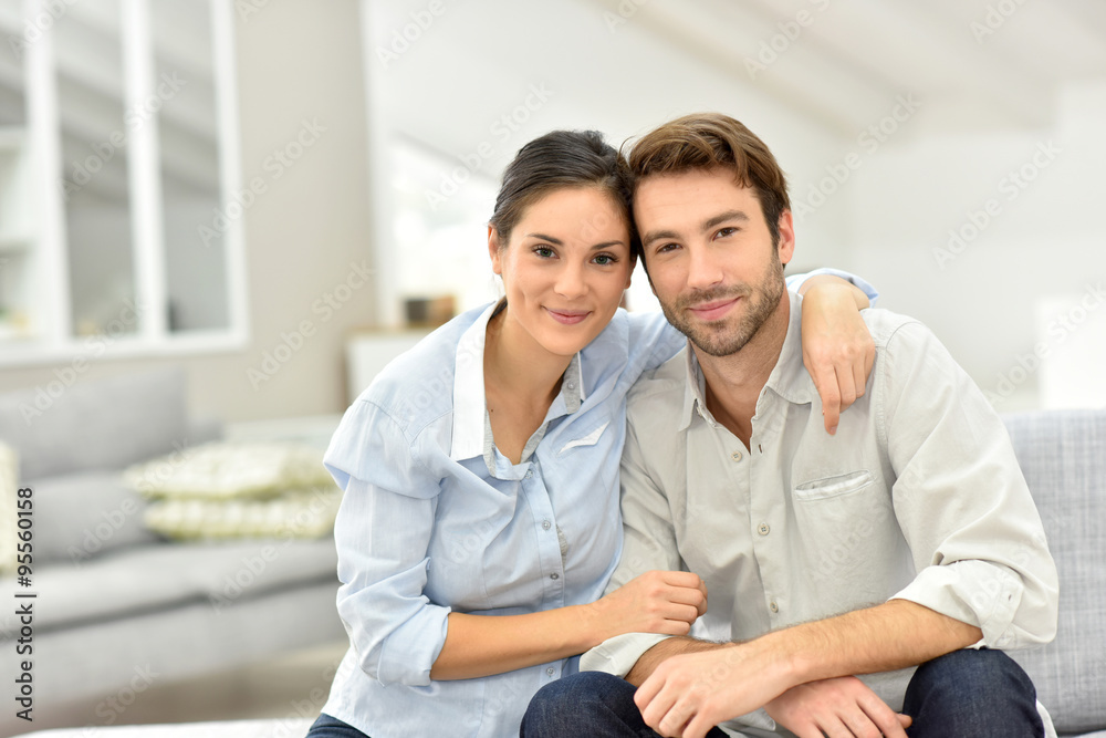 Portrait of cheerful couple sitting in sofa at home Portrait of cheerful couple sitting in sofa at home