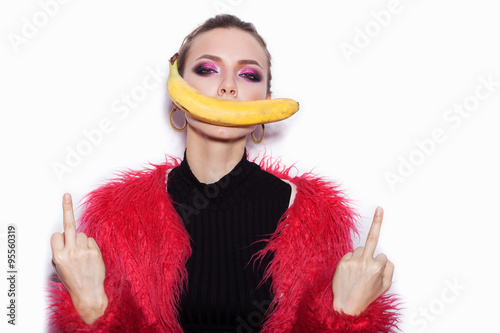  woman wearing pink fur coat making fun with banana