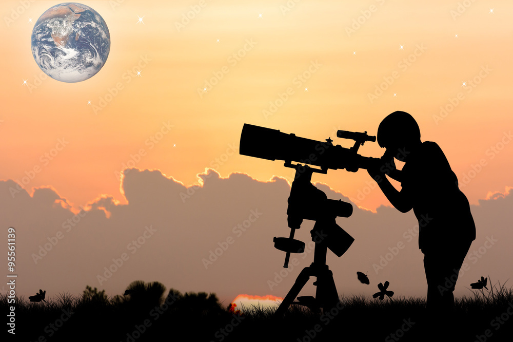 silhouette of little boy looking through a telescope at sunset background,the backdrop of the planet earth. Elements of this image furnished by NASA.