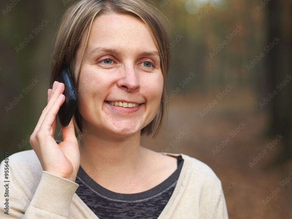 Happy smiling woman on the phone in the nature.