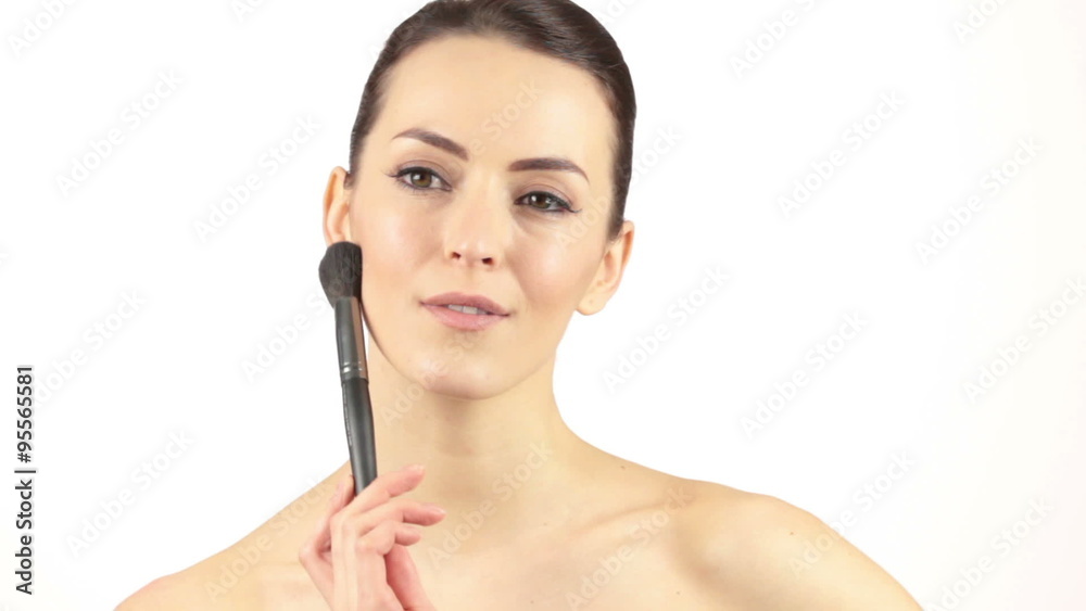 Beautiful young woman using a large make up brush to apply powder Beautiful young woman using a large make up brush to apply powder
